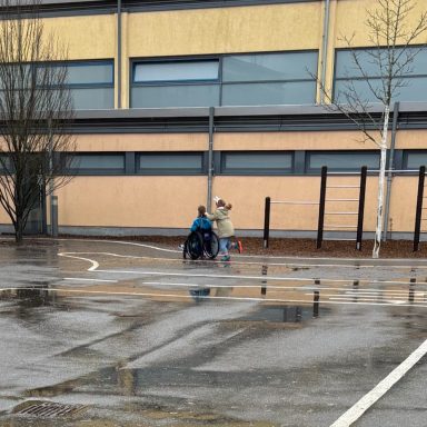 Eine Person im Rollstuhl auf einem Schulhof.